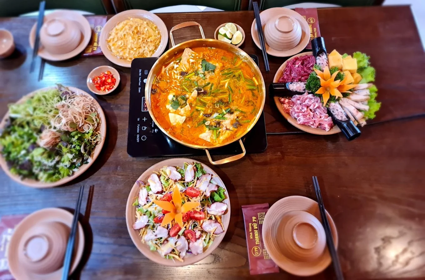 Mâm lẩu cua đồng tròn vị với bắp bò tươi, sụn non, giò tai, salad khai vị và mẹt rau sống tươi xanh.