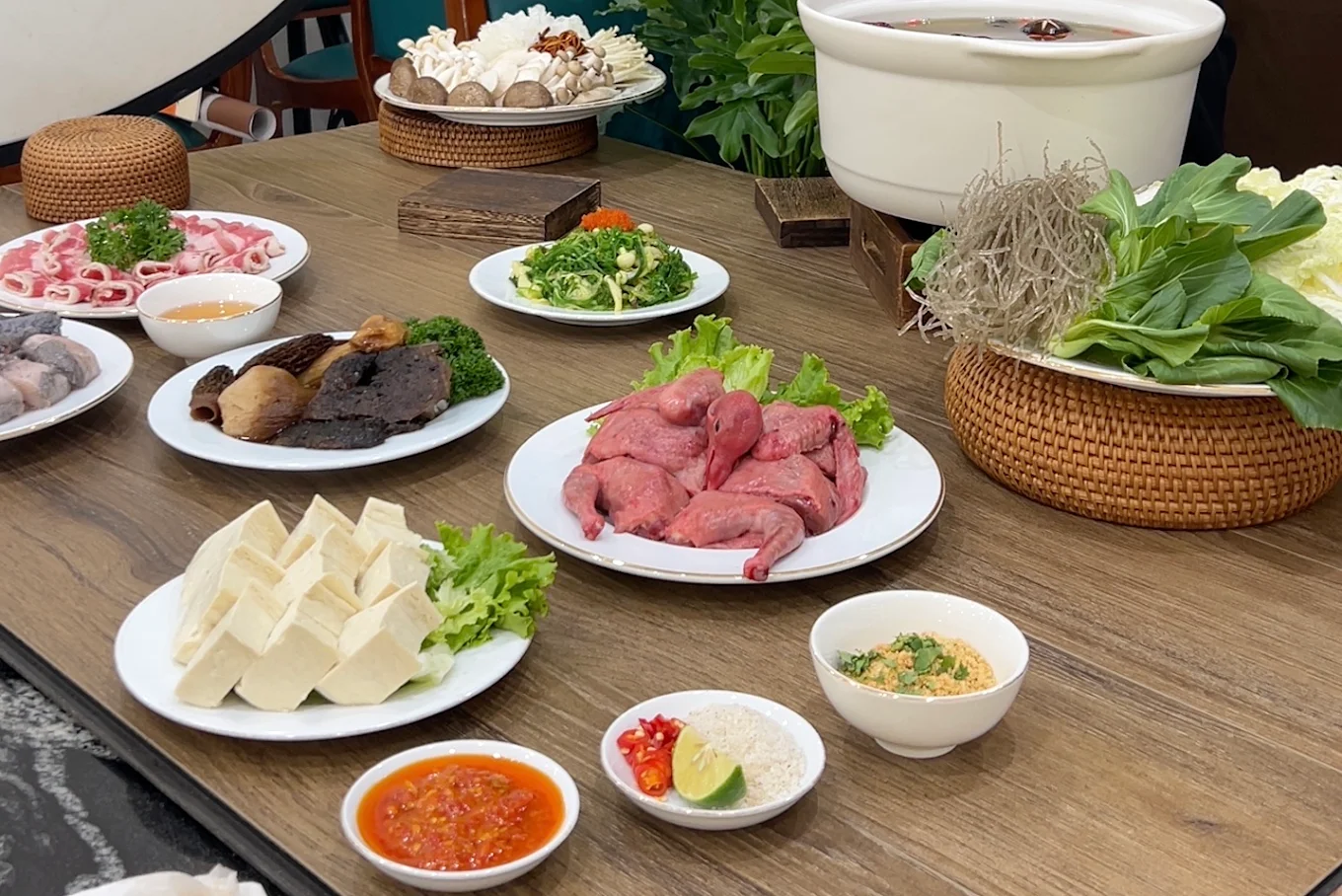 Bàn tiệc lẩu nấm đầy đặn với chim câu, ba chỉ bò Mỹ, các loại nấm quý và rau xanh tươi non.