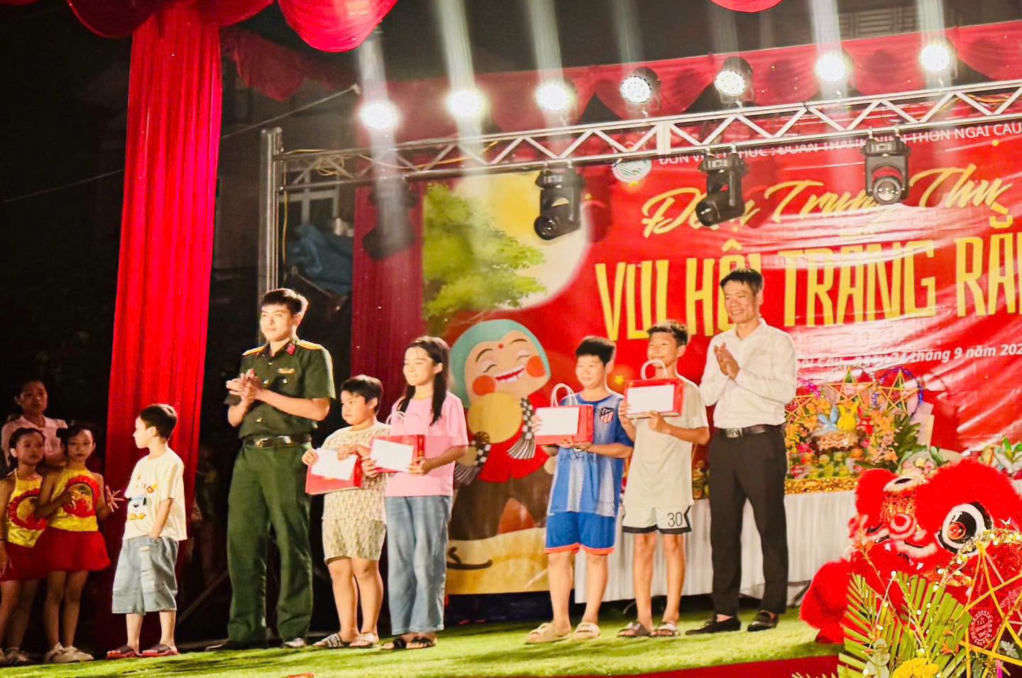 Đại diện lãnh đạo xã An Khánh và đơn vị quân đội đóng quân trên địa bàn trao quà cho các cháu thiếu nhi thôn Ngãi Cầu.