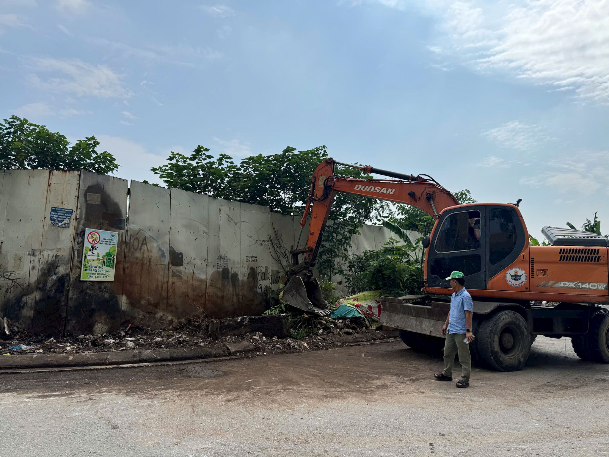 Lực lượng chức năng xã An Khánh huy động máy xúc chuyên dụng để giải tỏa lượng lớn rác thải tích tụ tại cổng phụ The Golden An Khánh.