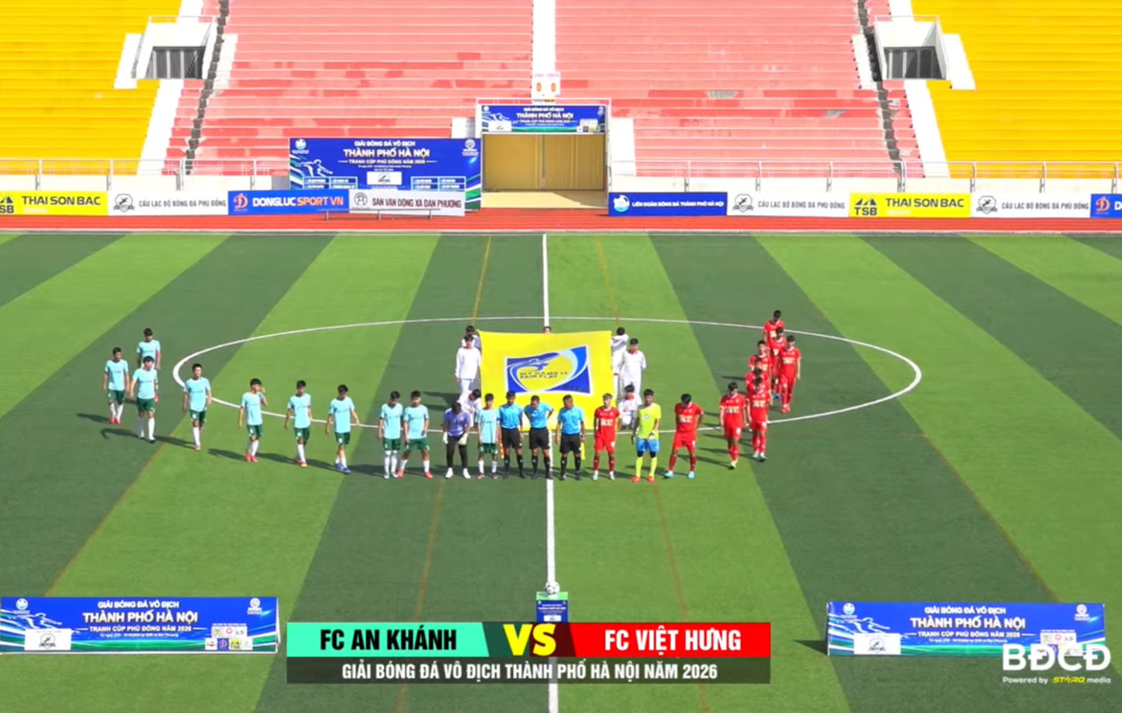 Đội hình xuất phát của FC An Khánh (áo xanh ngọc) và FC Việt Hưng (áo đỏ) cùng tổ trọng tài thực hiện các thủ tục trước giờ bóng lăn.