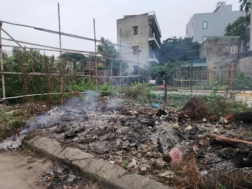 Đống tro tàn đen nhẻm, khói vẫn âm ỉ bốc lên bên vệ đường cạnh khu dân cư sau khi ngọn lửa tàn.