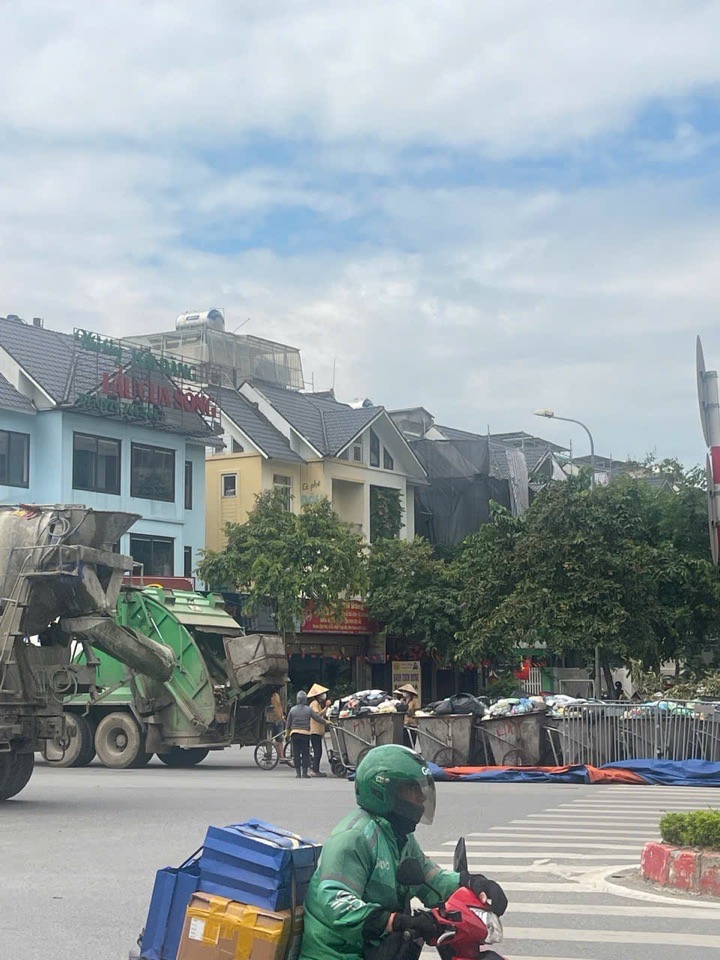 Các phương tiện xe máy và xe tải nặng phải luồn lách qua điểm tập kết rác cồng kềnh tại ngã tư.