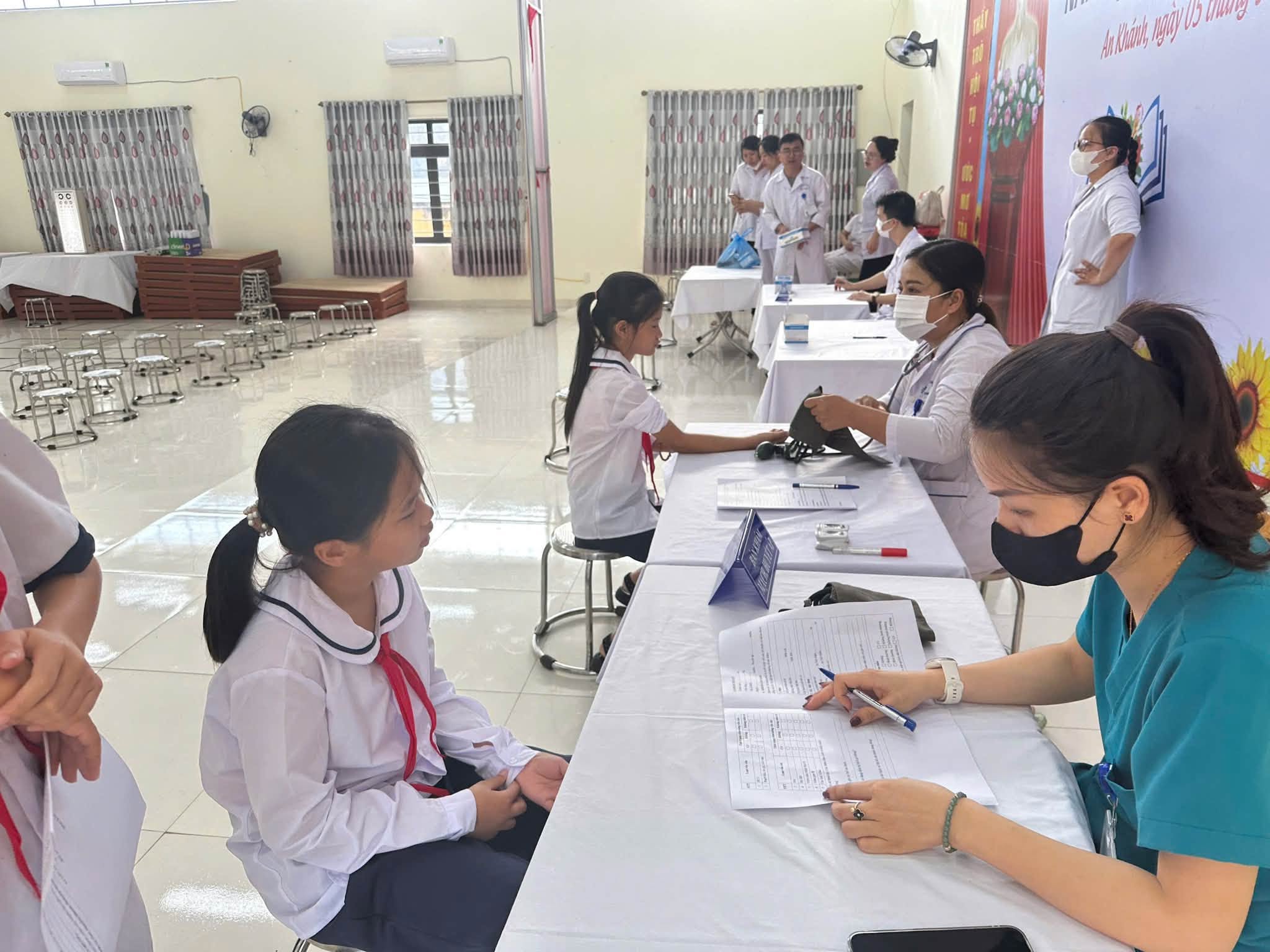 Cán bộ y tế tập trung ghi chép kết quả phân loại sức khỏe vào phiếu khám của từng học sinh.