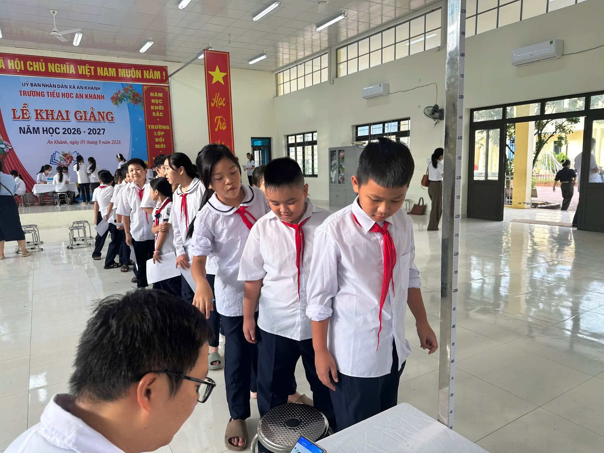 Các em học sinh nghiêm túc xếp hàng trật tự chờ tới lượt đo các chỉ số chiều cao và cân nặng.
