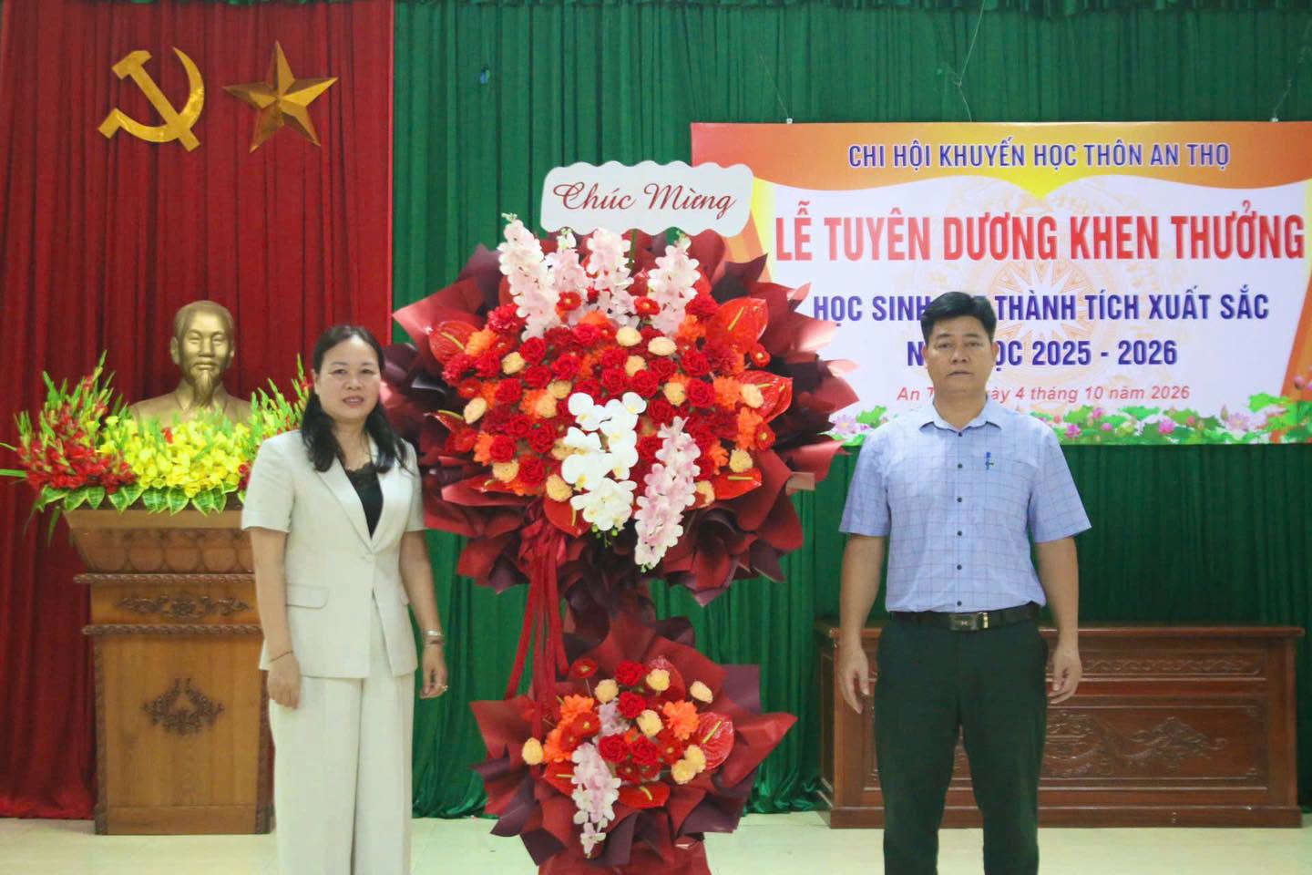 Đại diện lãnh đạo thôn An Thọ chụp ảnh lưu niệm cùng lẵng hoa tươi thắm chúc mừng thành công của phong trào khuyến học.