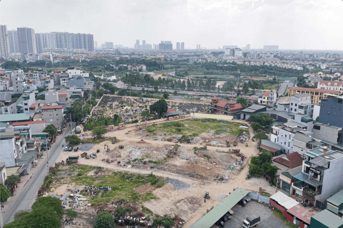Ranh giới giữa các lô đất dịch vụ và khu nghĩa trang rộng lớn chỉ cách nhau một bức tường gạch và lối đi nhỏ.
