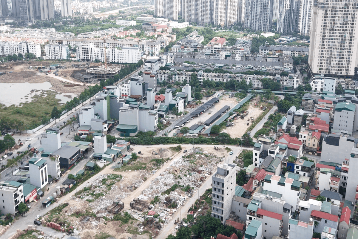 Ranh giới khu đất nằm liền kề các dãy biệt thự, nhà ống cao tầng và khu vực bãi đỗ xe tạm thời.