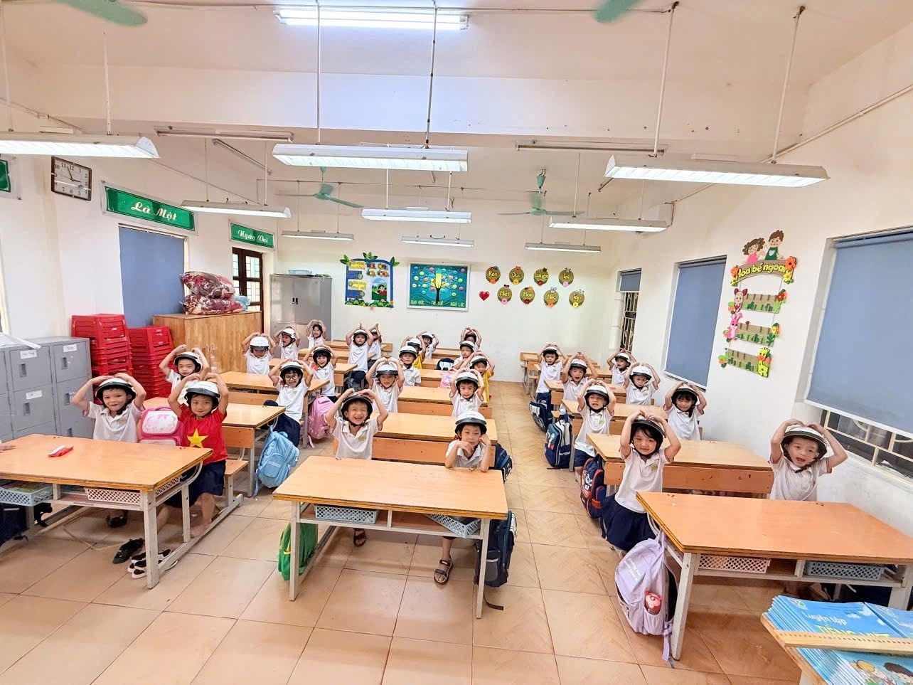 Các bạn nhỏ chăm chú thực hành đội mũ bảo hiểm theo đúng hướng dẫn của cô giáo chủ nhiệm.