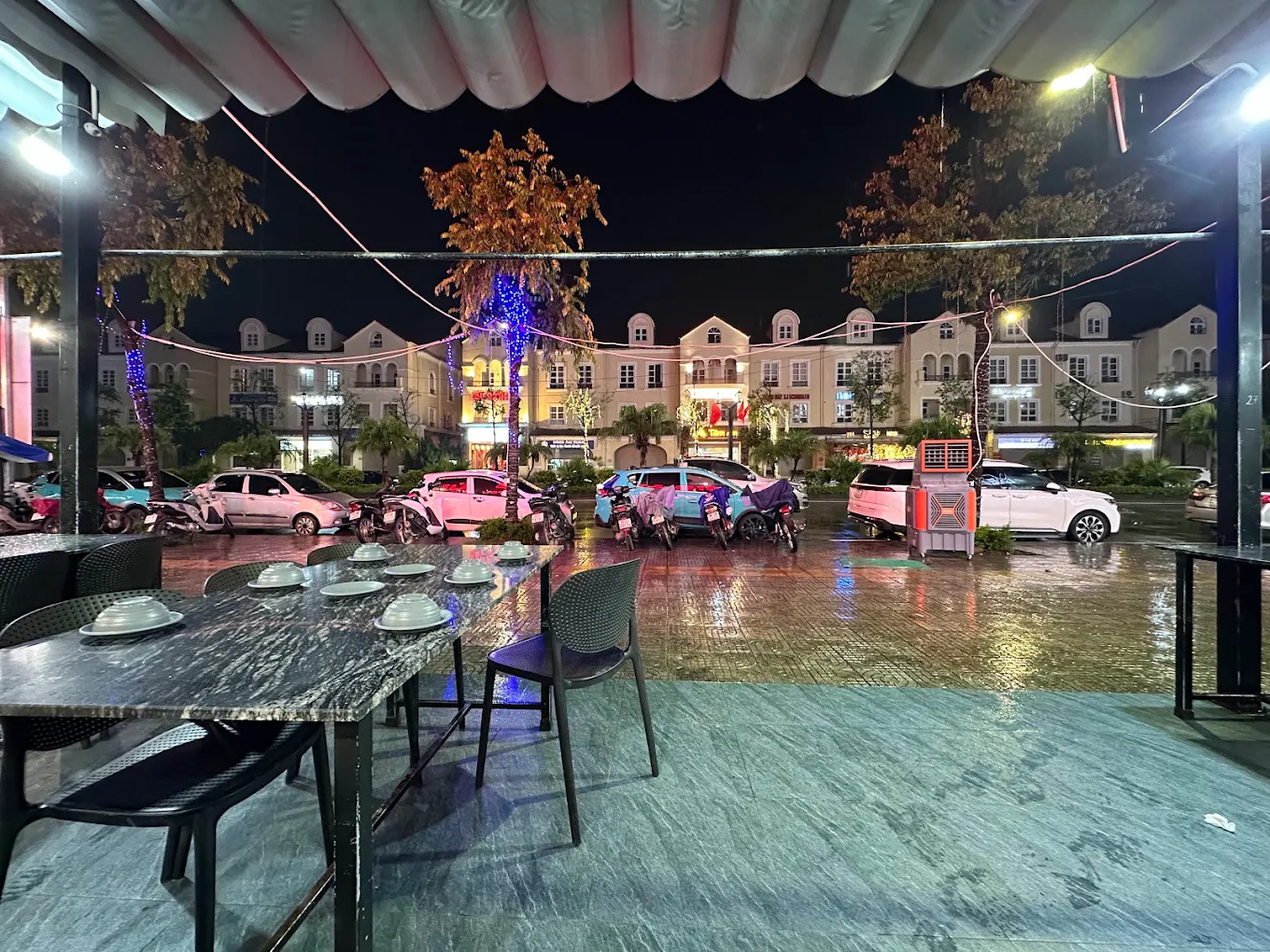 Một góc không gian dưới mái che bạt xếp, nhìn ra trục đường đôi Nam An Khánh thơ mộng sau cơn mưa.